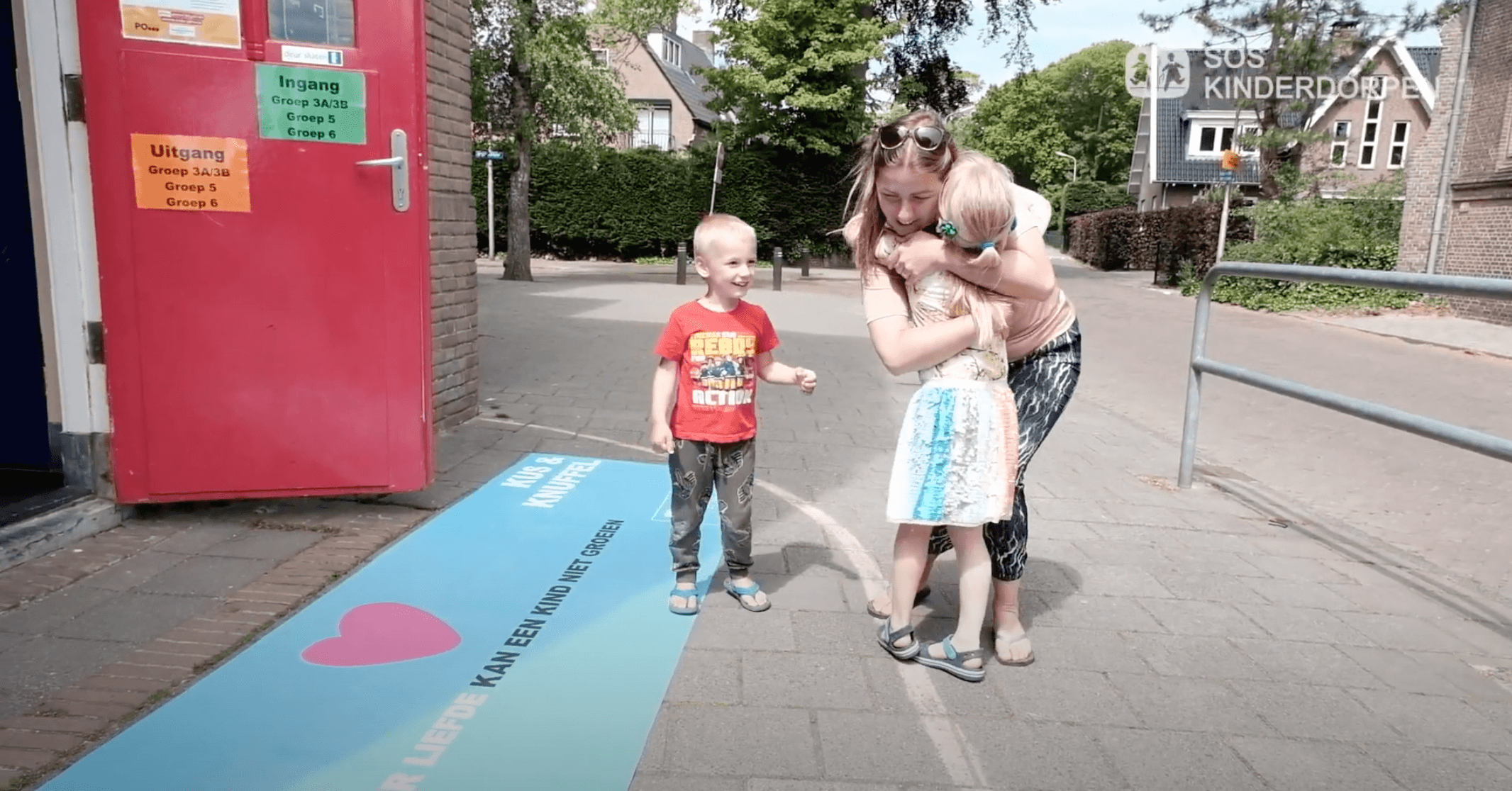 Coronaknuffelmat bij school met moeder met kinderen