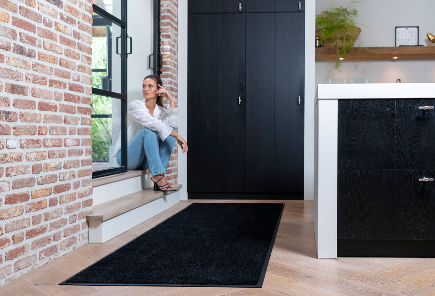 Zwarte binnenmat in hal met vrouw in raam